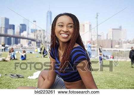 Smiling Black woman sitting in grass at waterfront View Large Photo Image Stock Image - Smiling Black woman sitting in grass at waterfront. Fotosearch