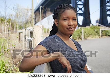 Smiling Black woman sitting on bench outdoors View Large Photo Image Stock Image - Smiling Black woman sitting on bench outdoors. Fotosearch