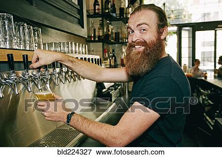 Smiling Caucasian bartender pouring beer View Large Photo Image Stock Photo - Smiling Caucasian bartender pouring beer. Fotosearch
