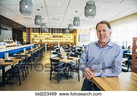 Smiling Caucasian man leaning on counter at restaurant View Large Photo Image Stock Photo - Smiling Caucasian man leaning on counter at restaurant. Fotosearch