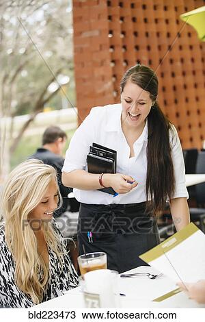 Stock Image - Smiling Caucasian waitress assisting customer. Fotosearch