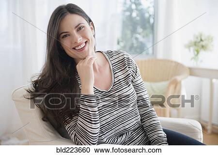 Stock Image - Smiling Caucasian woman sitting in armchair. Fotosearch