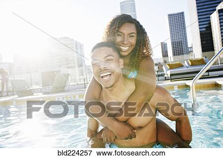 Stock Photo - Smiling couple enjoying urban swimming pool. Fotosearch