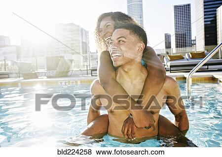 Stock Photo - Smiling couple enjoying urban swimming pool. Fotosearch