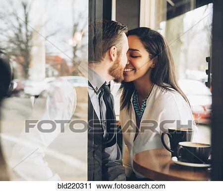 Stock Image - Smiling couple kissing in cafe. Fotosearch
