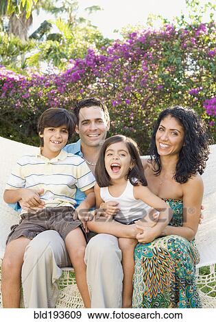 Stock Photo - Smiling family sitting in garden. Fotosearch