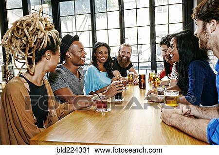 Smiling friends drinking at table in bar View Large Photo Image Stock Image - Smiling friends drinking at table in bar. Fotosearch