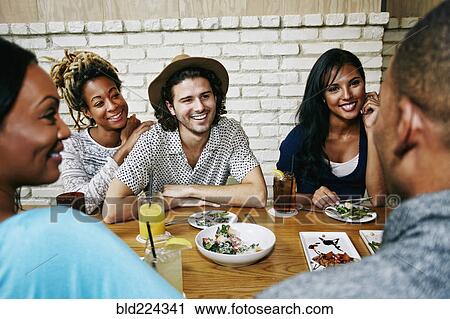 Smiling friends enjoying food and cocktails at table in bar View Large Photo Image Stock Image - Smiling friends enjoying food and cocktails at table in bar. Fotosearch