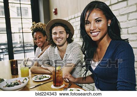 Smiling friends enjoying food and cocktails at table in bar View Large Photo Image Stock Image - Smiling friends enjoying food and cocktails at table in bar. Fotosearch