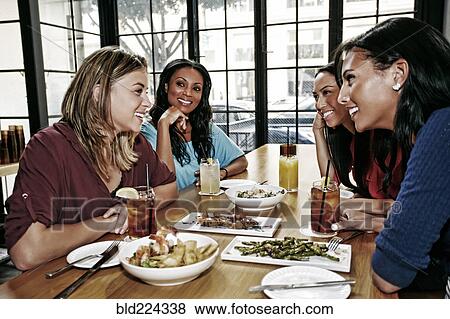 Smiling friends enjoying food and cocktails at table in bar View Large Photo Image Stock Photo - Smiling friends enjoying food and cocktails at table in bar. Fotosearch