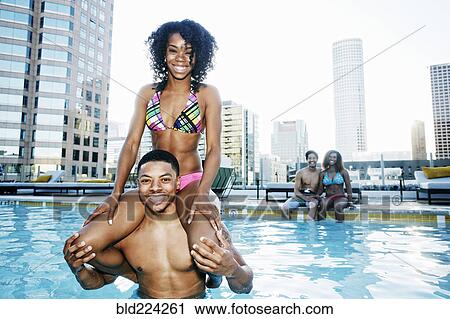 Stock Image - Smiling friends enjoying urban swimming pool. Fotosearch