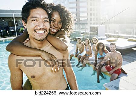 Stock Photograph - Smiling friends enjoying urban swimming pool. Fotosearch