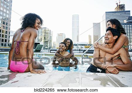 Stock Photography - Smiling friends enjoying urban swimming pool. Fotosearch