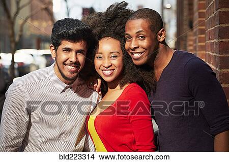 Picture - Smiling friends posing on city sidewalk. Fotosearch