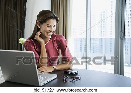 Stock Photo - Smiling Hispanic woman looking at cell phone. Fotosearch