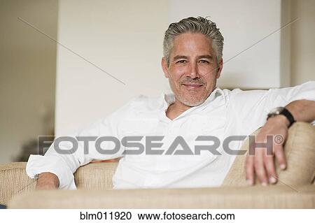 Stock Image - Smiling man relaxing on sofa. Fotosearch