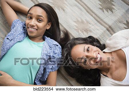 Picture - Smiling mother and daughter laying on carpet. Fotosearch