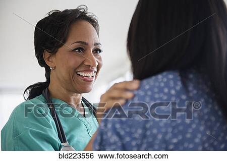 Smiling nurse comforting patient View Large Photo Image Stock Photograph - Smiling nurse comforting patient. Fotosearch