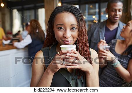 Picture - Smiling woman drinking coffee in cafe. Fotosearch