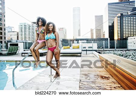 Stock Image - Smiling woman standing poolside at urban swimming pool. Fotosearch