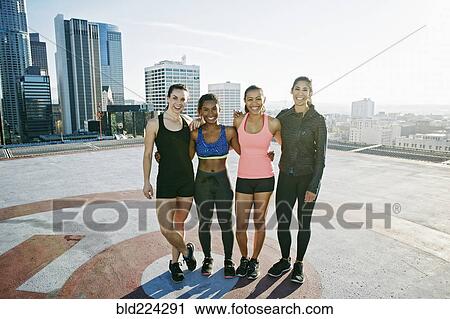 Stock Image - Smiling women posing on urban rooftop. Fotosearch