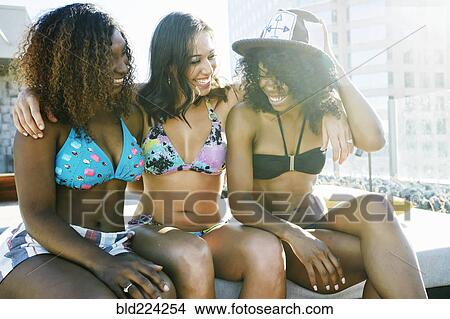Picture - Smiling women wearing bikinis at urban poolside. Fotosearch