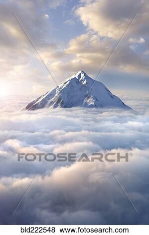 Stock Photo - Snow-covered mountaintop above clouds. Fotosearch