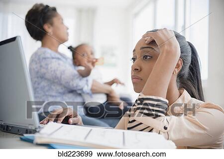 Stock Photo - Stressed Black woman paying bills using laptop. Fotosearch
