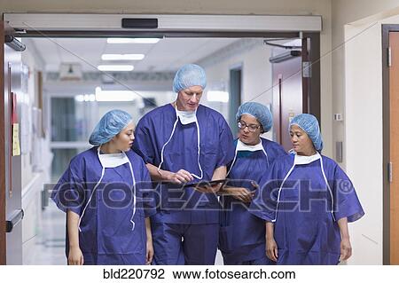 Stock Image - Surgeons using digital tablet in hospital hallway. Fotosearch