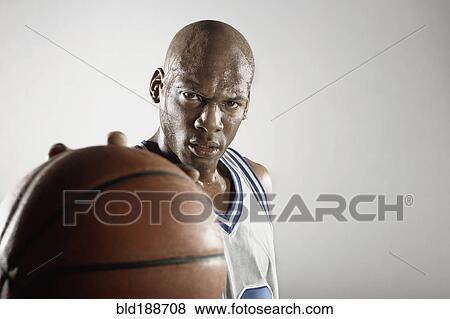 Stock Photo - Sweating Hispanic basketball player holding basketball. Fotosearch
