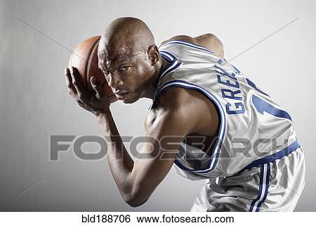 Stock Photograph - Sweating Hispanic basketball player holding basketball. Fotosearch