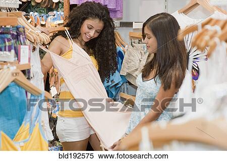 Stock Photography - Teenage girls looking at dress in store. Fotosearch