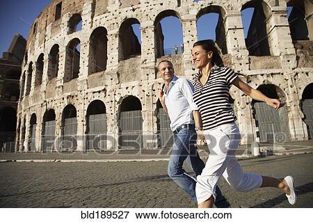 Stock Photo - Tourist couple running near coliseum. Fotosearch