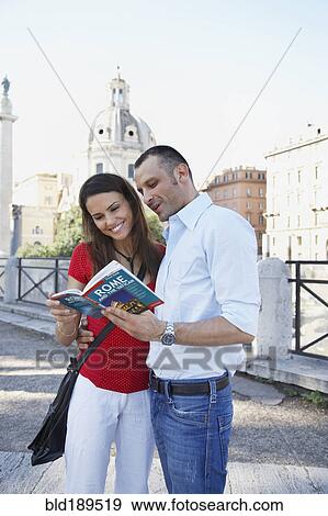 Stock Photo - Tourists reading guidebook outdoors. Fotosearch