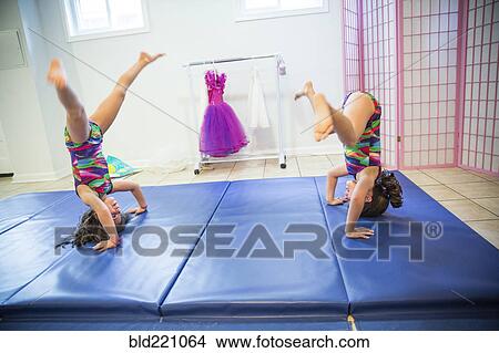 Picture - Twin sisters tumbling in gymnastics. Fotosearch