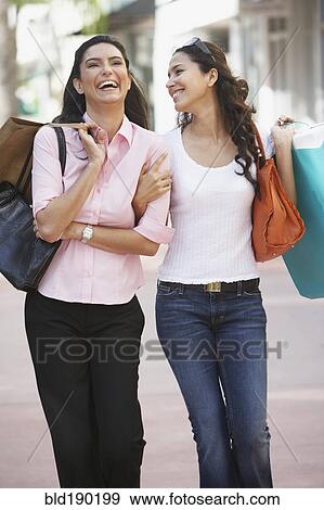Stock Photo - Two Hispanic women with shopping bags. Fotosearch