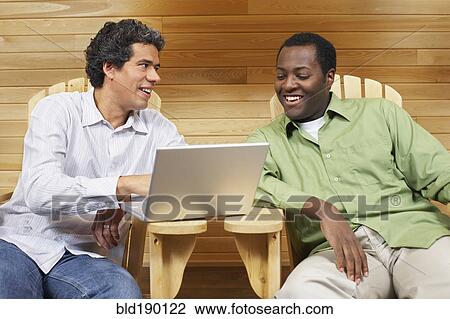 Stock Image - Two multi-ethnic men looking at laptop. Fotosearch