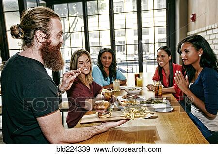 Waiter serving foods to friends at table in bar View Large Photo Image Stock Photo - Waiter serving foods to friends at table in bar. Fotosearch
