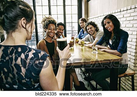 Waitress serving smiling friends at table in bar View Large Photo Image Stock Photography - Waitress serving smiling friends at table in bar. Fotosearch