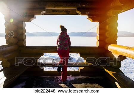 Stock Photo - Woman admiring snow from lodge balcony in winter. Fotosearch