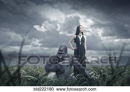 Stock Image - Woman and gorilla in remote field. Fotosearch
