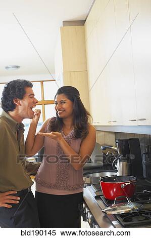 Stock Photography - Woman feeding husband in kitchen. Fotosearch