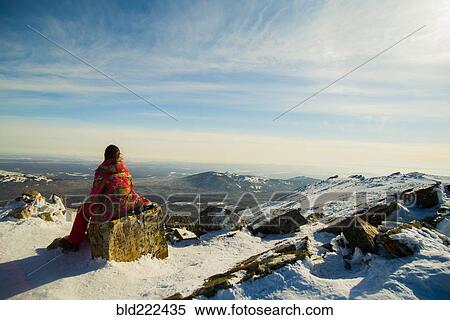 Stock Photography - Woman hiker sitting on mountain rock in winter. Fotosearch