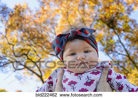 Woman holding baby girl against autumn tree View Large Photo Image Stock Image - Woman holding baby girl against autumn tree. Fotosearch