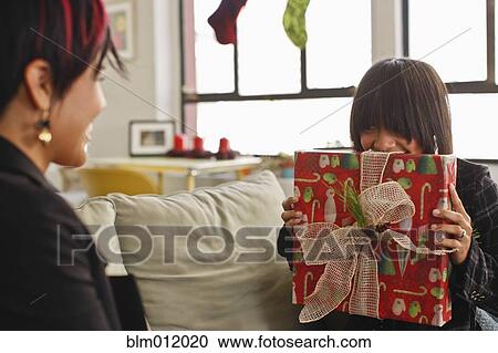 Stock Image - Woman holding Christmas gift for friend. Fotosearch