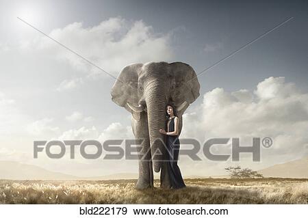 Stock Photo - Woman hugging elephant in remote field. Fotosearch