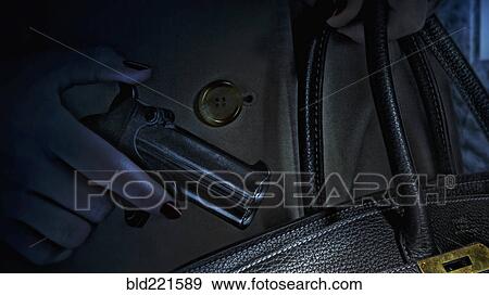 Stock Photo - Woman placing gun in purse. Fotosearch