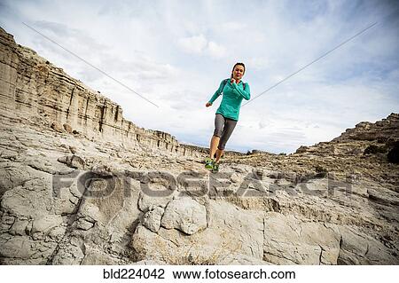 Stock Image - Woman running in canyon. Fotosearch