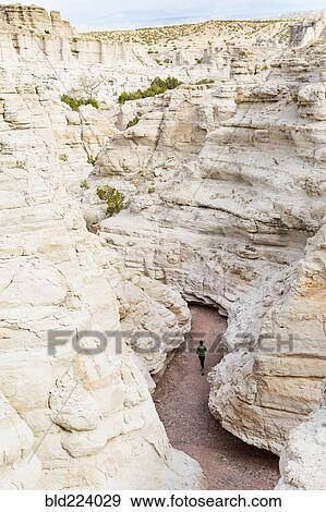 Stock Photo - Woman running in canyon wearing backpack. Fotosearch