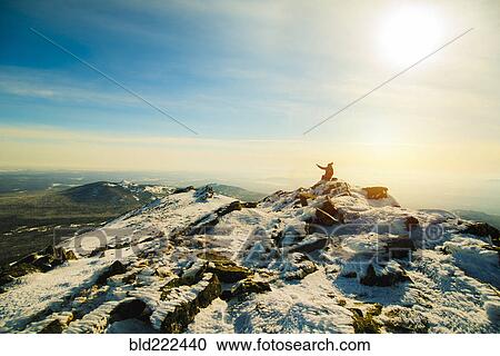 Stock Image - Woman sitting on mountain in winter. Fotosearch
